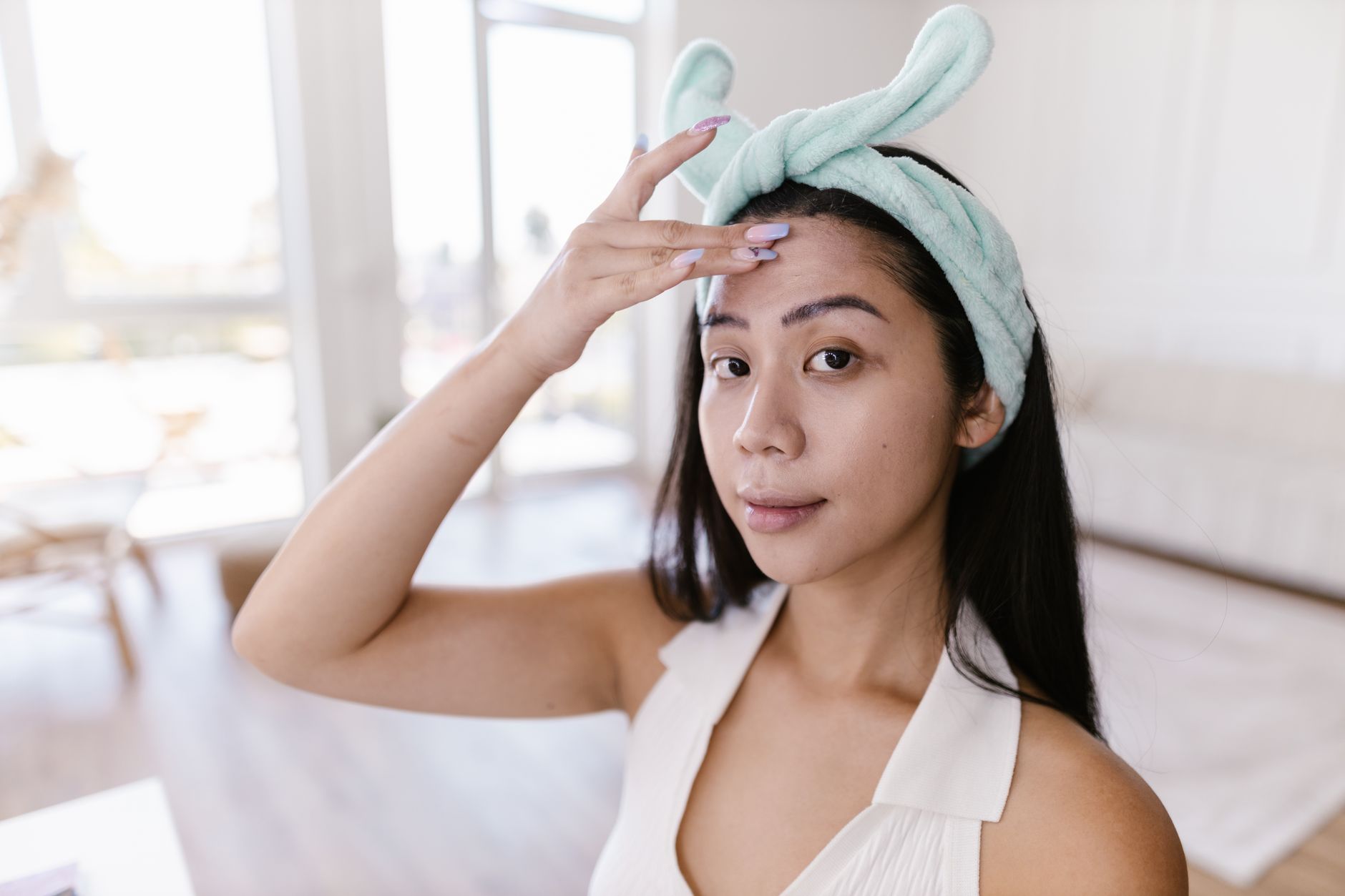 A young woman applies skincare products at home, emphasizing her daily beauty routine.