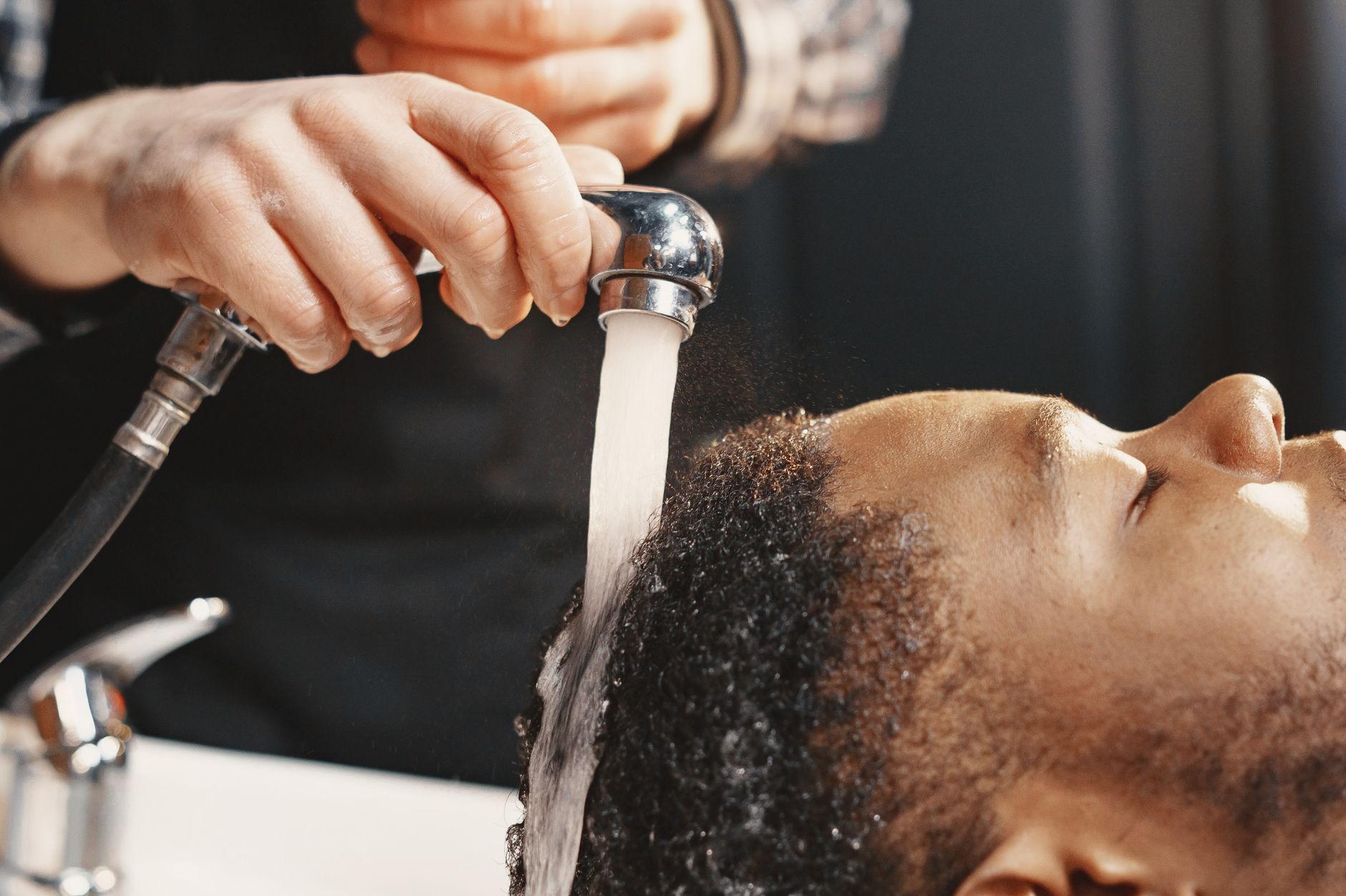 Close-up of a man receiving a professional hair wash at a salon.
