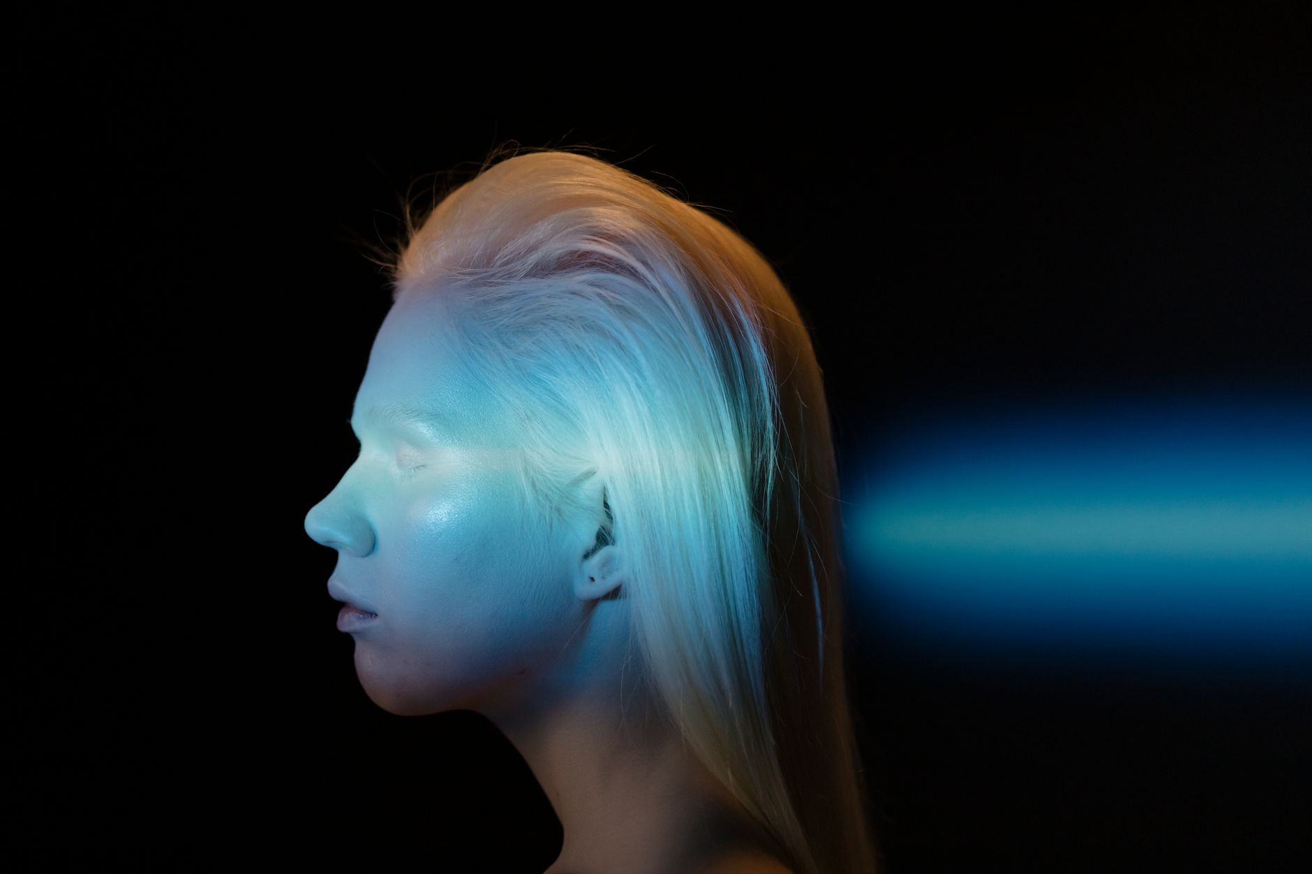 Artistic side profile of a woman with blue light projection on a dark background.