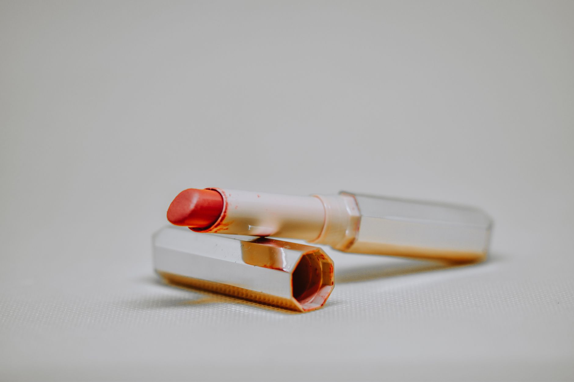 Close-up of a red lipstick with a sleek case on a neutral backdrop, perfect for beauty product photography.