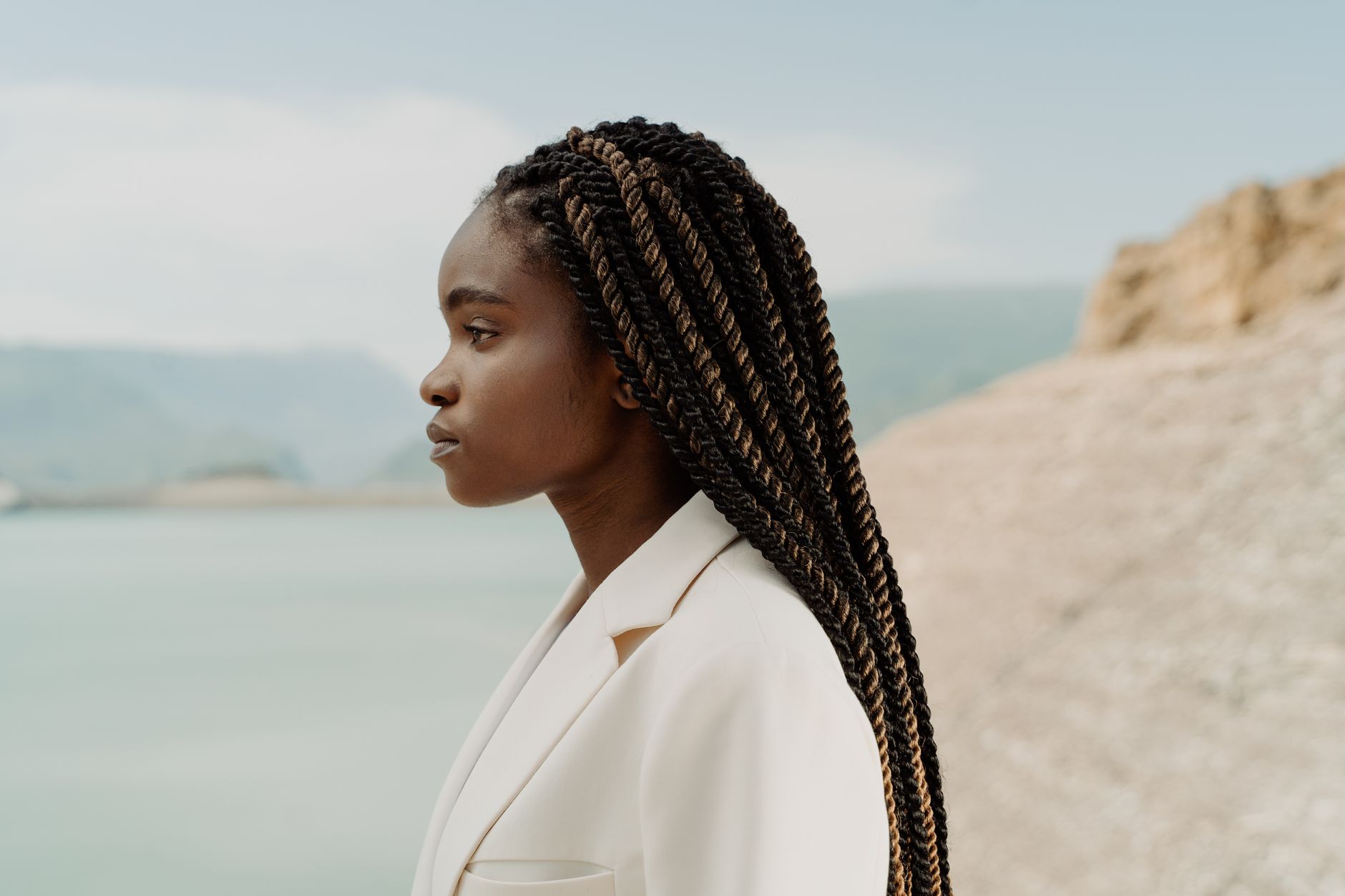 Profile of a stylish woman with afro braids in a natural outdoor setting.
