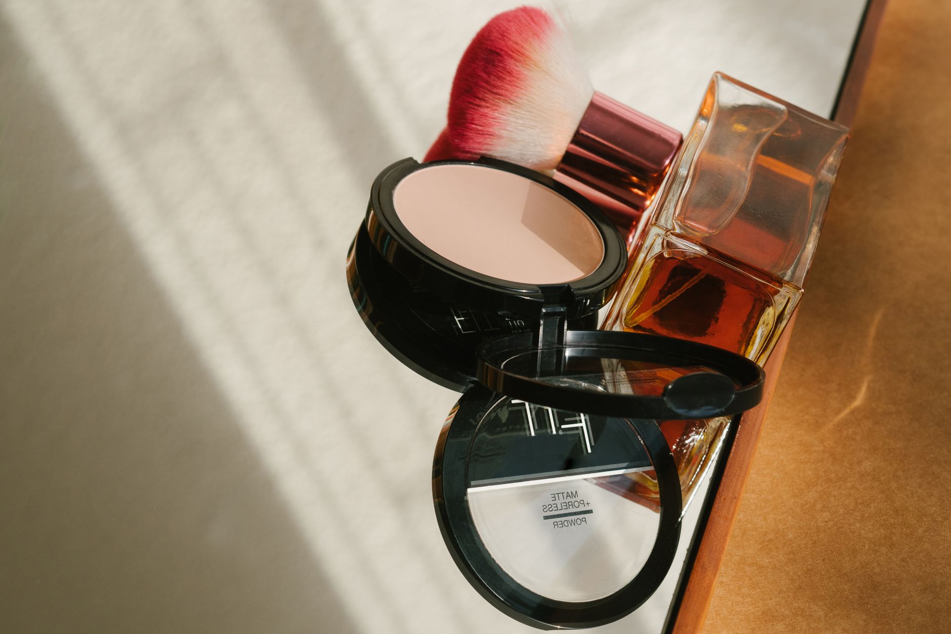 Stylish still-life of makeup and perfume on a sunlit surface, exuding elegance.