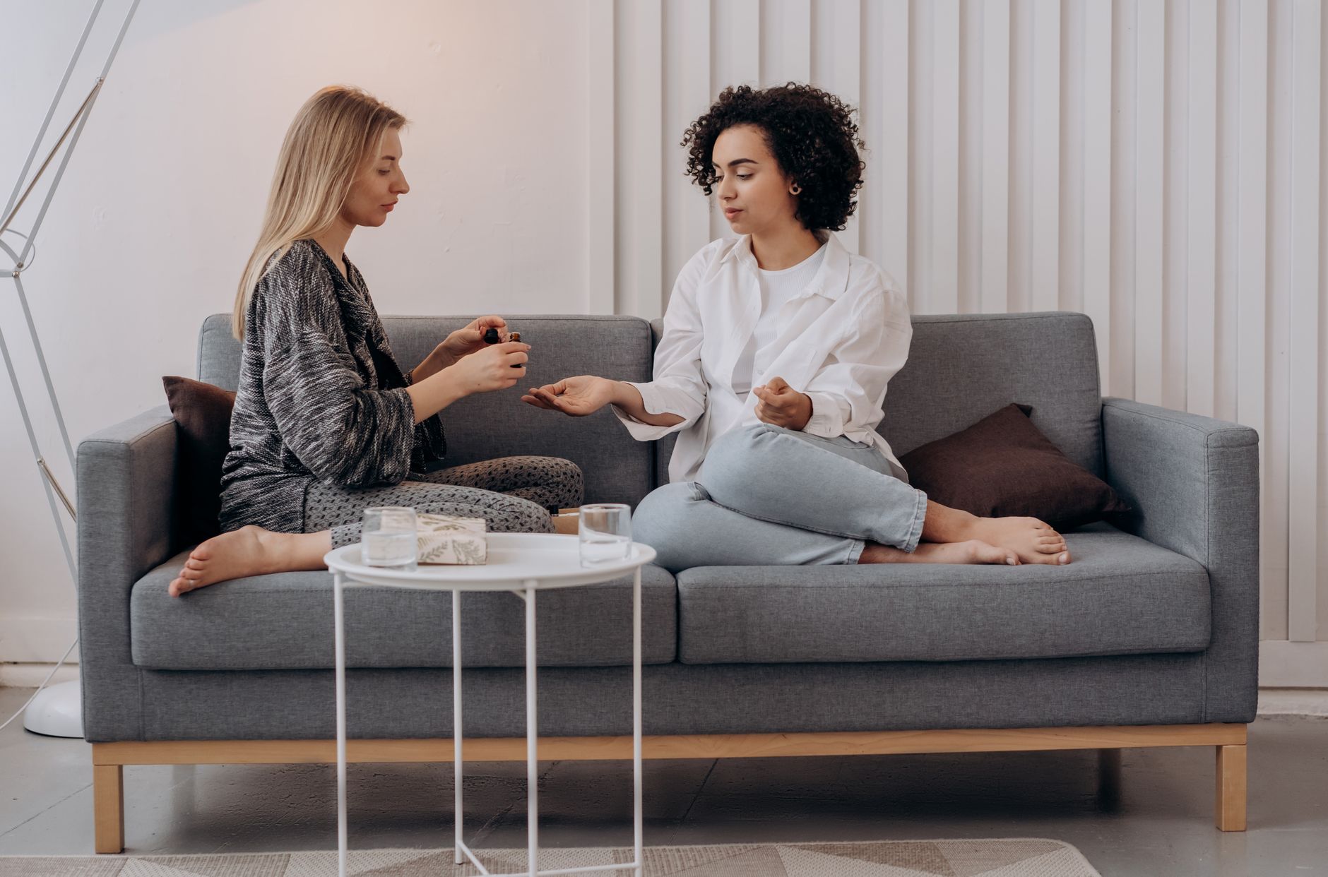 Two women on a couch practicing aromatherapy, sharing a moment of relaxation and wellness indoors.