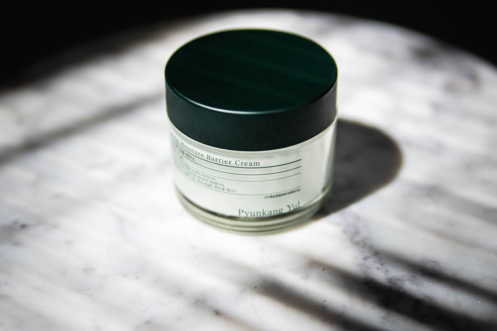 Close-up of a moisture barrier cream jar with stylish packaging on marble.